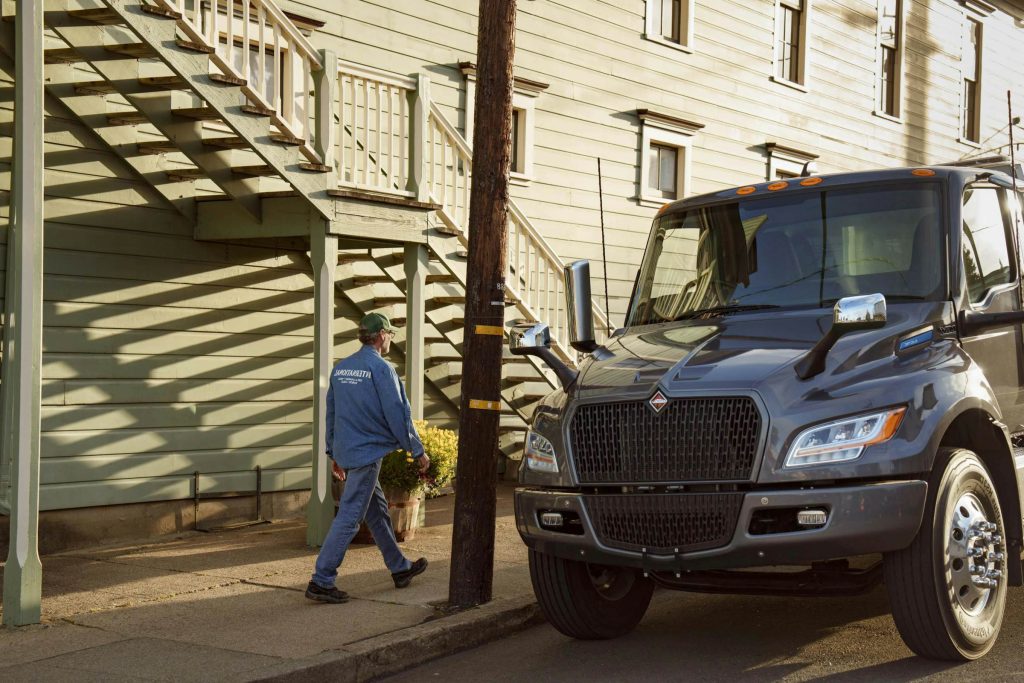 international-eMV-foreground-parked-male-driver-walking-town-tomales-240318-1914